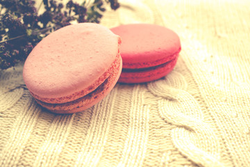 Fresh colorful macaroons on woolen knitted background.