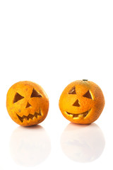 Food art creative concept. Halloween scary face carved into yellow orange fruit with food decorations isolated over a white background