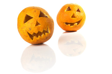 Food art creative concept. Halloween scary face carved into yellow orange fruit with food decorations isolated over a white background