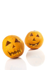 Food art creative concept. Halloween scary face carved into yellow orange fruit with food decorations isolated over a white background