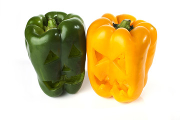 Food art creative concept. Halloween scary face carved into green capsicum vegetables isolated over a white background.