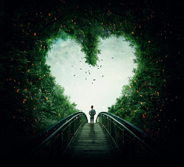 Boy walking on a bridge through the heart shape woods, following the light. Follow your heart...
