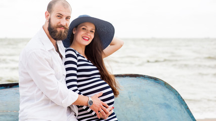 Obraz premium Beautiful young pregnant woman with man on the beach feel peace and tranquility