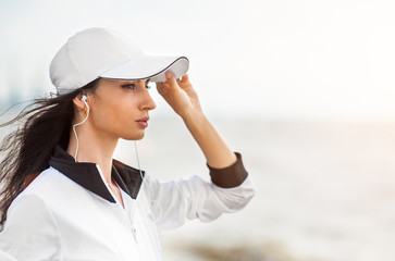 Young woman on beach listening to music in earphones from smart phone mp3 player smartphone armband, Female training for marathon on beautiful beach. Mixed race Asian woman.