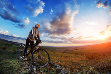 Naklejka na ściany i meble cyclist standing with mountain bike on trail at sunset