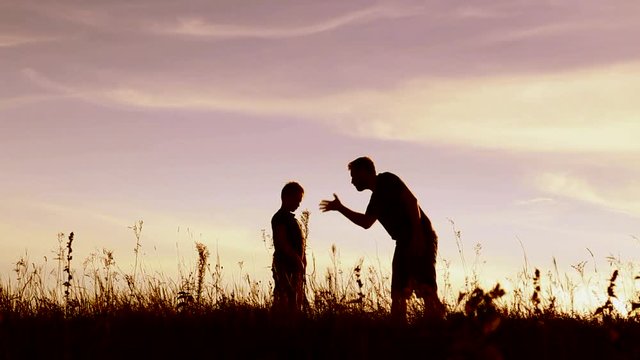 Angry parent and his child over sunset sky background. Anonymous emotional father talking and screaming at little guilty son outside. Feelings and emotions concept. Real time full hd video footage.