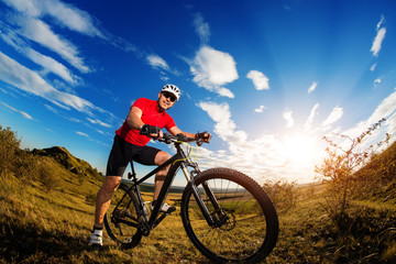 Fototapeta na wymiar cyclist standing with mountain bike on trail at sunset