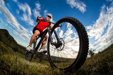 Fototapeta na wymiar cyclist riding mountain bike on rocky trail at sunrise