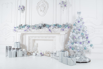 the composition of the gifts, the Christmas tree and Christmas decorations and the fireplace in white interior