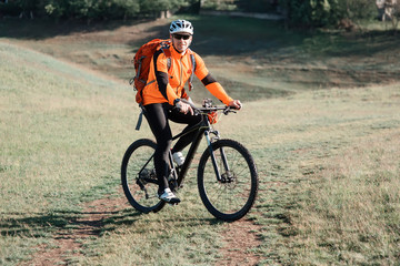 Fototapeta premium Bicycle tourist with loaded bike riding on green meadow