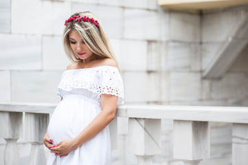 Beautiful lovely girl wearing her first child in the stomach and is looking forward to his birth. Strolling in the park, enjoy nature and quietness