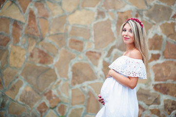 Beautiful lovely girl wearing her first child in the stomach and is looking forward to his birth. Strolling in the park, enjoy nature and quietness
