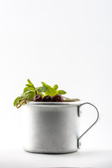 Drink with leaves of mint and cherries in the metal mug isolated on white background
