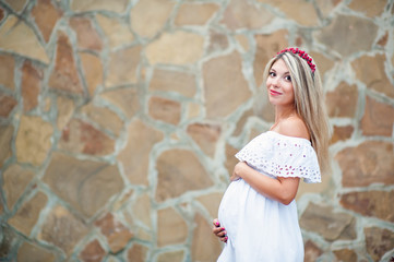 Beautiful lovely girl wearing her first child in the stomach and is looking forward to his birth. Strolling in the park, enjoy nature and quietness
