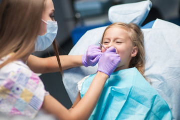 Dentist curing a child patient in the dental office in a pleasant environment. There are specialized equipment to treat all types of dental diseases in the office.