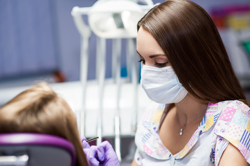 Dentist curing a woman patient in the dental office in a pleasant environment. There are specialized equipment to treat all types of dental diseases in the office.