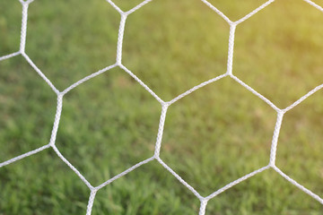 Fototapeta premium Detail of football net with sunlight in the field background, Football equipment