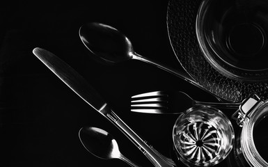 Cutlery, glare on a dark background.