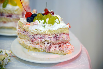 Piece of sliced white festive Cake with cream and fruit. Whipped cream in the shape of a rose sprinkled with strawberries and raspberries on cakes. Sweet food for the anniversary.