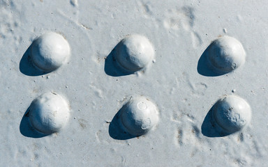 Fototapeta na wymiar Sunlit gray painted surface with six rivet heads