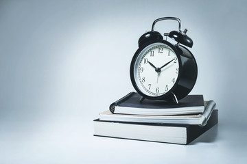 Alarm clock on stack notebook
