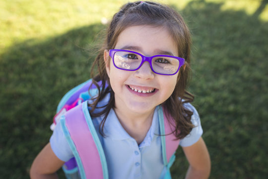 A girl wearing a uniform and a backpack is ready for her first day of school.