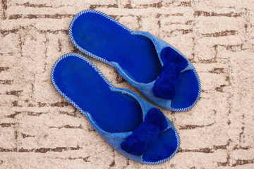 Fototapeta na wymiar Blue slippers on carpet. Welcome home concept.