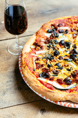 Homemade vegan zucchini, sun-dried tomato and black olive pizza with a glass of red wine