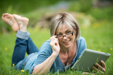 a nice woman of 40 years who is reading her emails in the garden