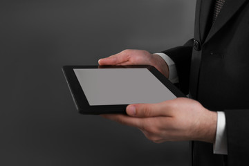 Businessman with tablet on grey background