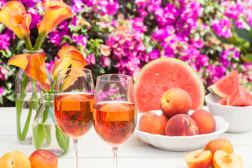glasses of rose wine, peaches, plums and watermelon at a picnic in the summer