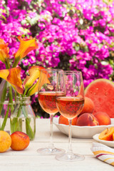 glasses of rose wine, peaches, plums and watermelon at a picnic in the summer