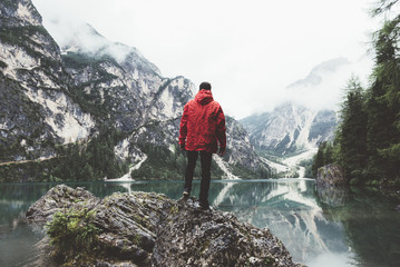 Man with red raincoat on a rock on Braies lake 
