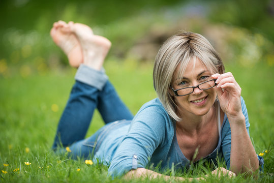 portrait of a woman of 50 years old lying in grass in park