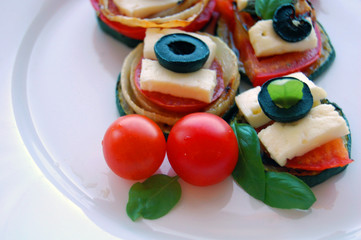 Grilled zucchini slices with tomatoes, black olives, goat cheese and basil