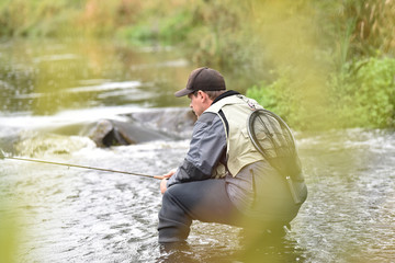 Fly-fisherman fishing in river
