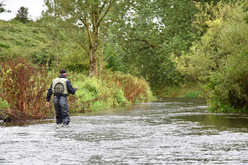 Back view of fly-fisherman fishing in river
