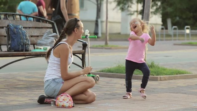 Little girl and her mother having fun with chalk in the park