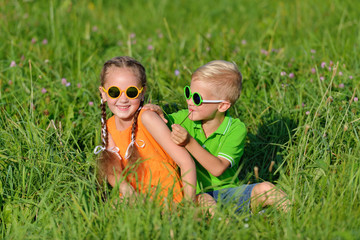 Group of happy children in sun glasses having fun in grass outdoors.