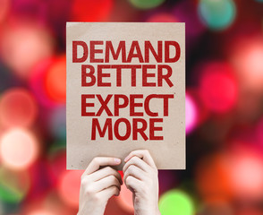 Demand Better Expect More placard with bokeh background