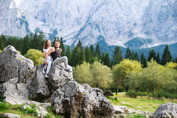 Couple of travelers on the Lago di Fusine lake with Mangart mountains on the background