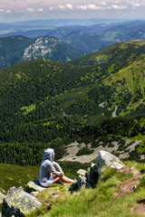 Fototapeta na wymiar Young woman sitting on mountain top. Jasna, Demianovska Dolina, Low Tatras, Slovakia. 