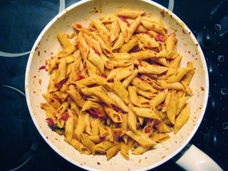 Pasta being cooked on a big white pan with an electric cooker.