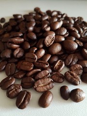 Grain of black coffee beans on a rough white background with beautiful natural lighting.