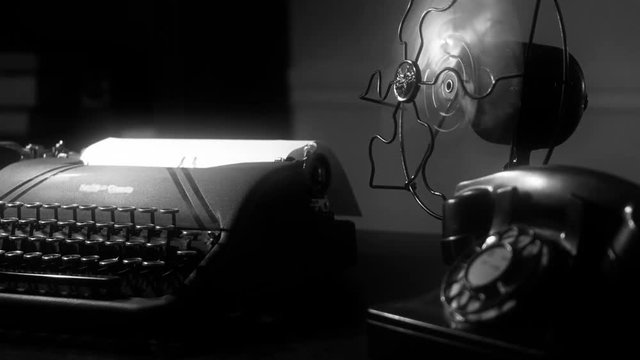 Radial dolly move of a desk with an old manual typewriter and vintage electric fan in dimly lit room. film Noir at 4k