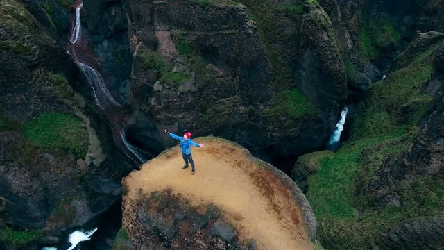 Man with raised hands up feeling freedom while standing at Fjadrargljufur canyon in Iceland