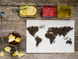 map of the world, lined with tea leaves on old paper. Eurasia, America, Australia, Africa. vintage. tea, cup, a towel, honey, raspberry jam with lemon on rustic wooden table. top view. flat lay