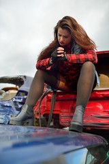 Fototapeta na wymiar long-haired brunette girl posing in a car scrappage