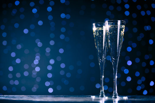 Two glasses of champagne on dark bokeh background