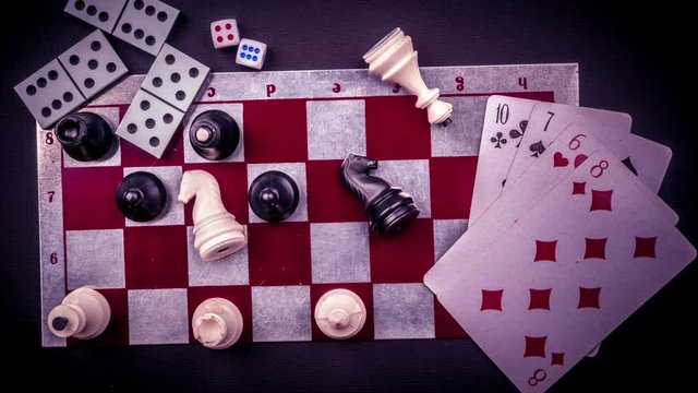 Stop motion animation of various board games and figurines over checkers board and dark background. Metaphor for gaming and gambling.